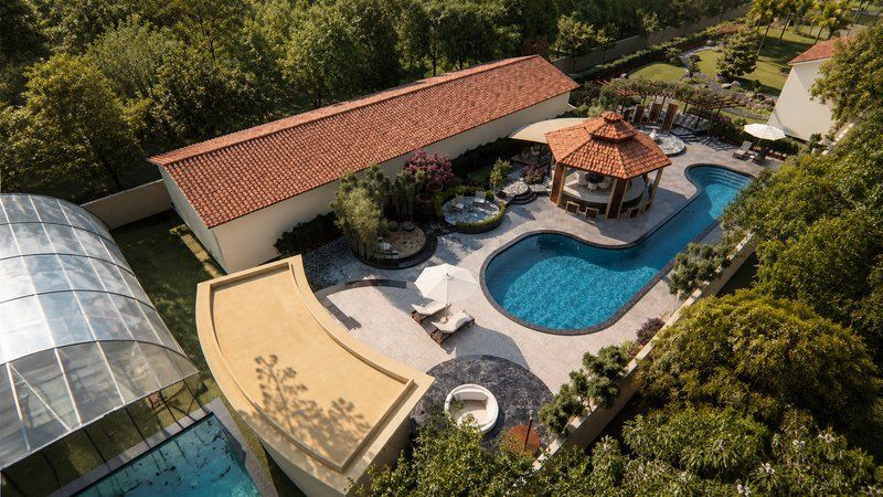 Aerial view of an Assam farmhouse with terracotta roof, swimming pool and garden pavilion